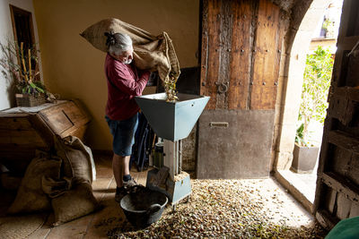 Male farmer pouring hand harvested almonds sack into a machine.