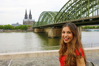 Portrait of woman against bridge over river in city