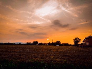 Scenic view of field against cloudy sky at sunset