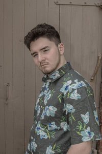 Portrait of young man standing against wall