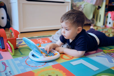 Curious little toddler playing with his toy computer