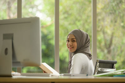 Portrait of smiling young woman sitting on table