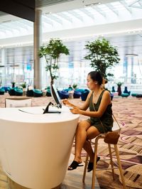 Full length of woman using computer at table in cafe