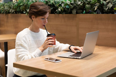 Side view of woman using laptop on table