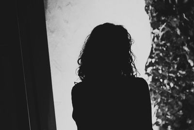 Rear view of silhouette woman standing against wall