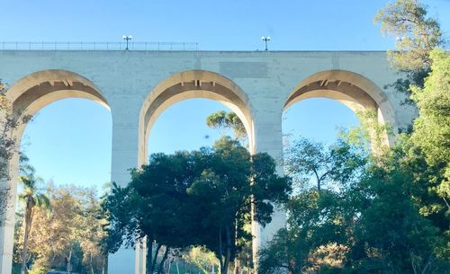 Low angle view of arch bridge against clear blue sky