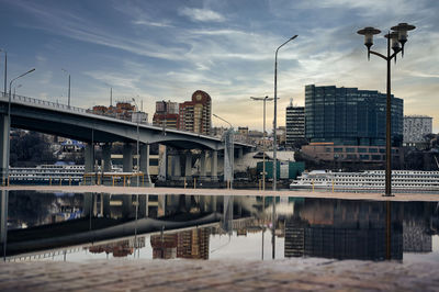 Bridge over river by buildings in city against sky