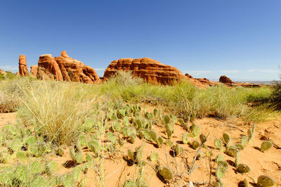 Rock formations on landscape against clear blue sky