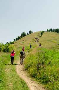 Rear view of people walking on footpath against sky