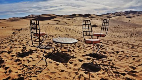 Deck chairs on beach against sky