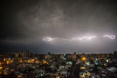 Lightning over illuminated buildings in city at night