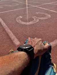 Midsection of man sitting by running track