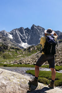 Rear view of hiker standing on rock by river in forest