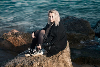 Portrait of woman sitting on rock at beach