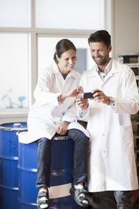 Happy engineers using mobile phone in manufacturing plant