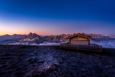 Scenic view of sea and snowcapped mountains against blue sky during sunset