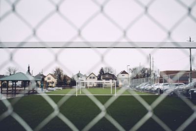 Close-up of chainlink fence against buildings in city