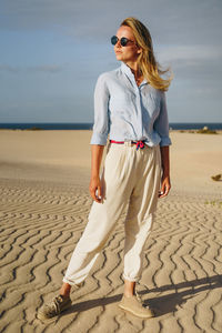 Full length of woman standing on sand in desert against sky