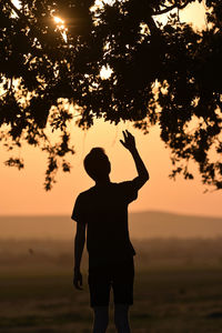 Rear view of silhouette man standing against sky during sunset