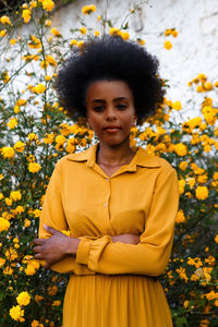 Portrait of woman standing by yellow flowers