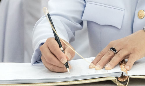 Midsection of businessman writing in file on desk at office