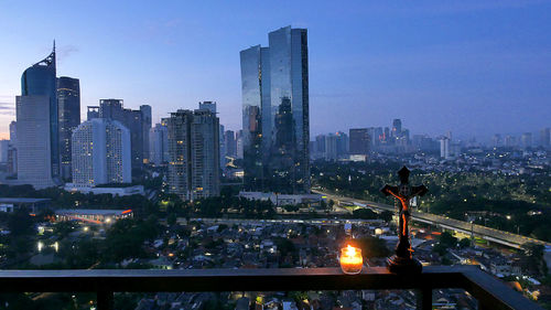 Illuminated buildings in city against sky at dusk