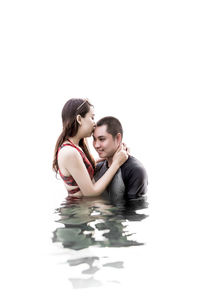 Young couple kissing against white background