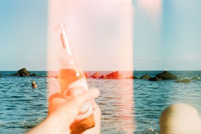 Low section of woman swimming in sea against sky