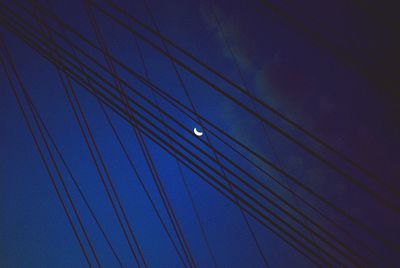 Low angle view of bridge cables against blue sky