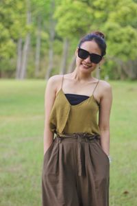 Young woman wearing sunglasses standing on field