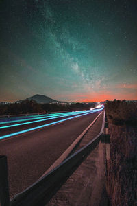 Light trails on road against sky at night