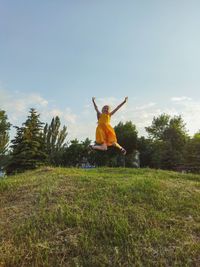 Girl jumping on field against sky