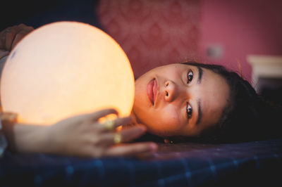 Portrait of woman with illuminated sphere at home