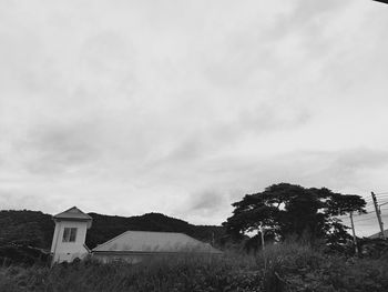 Trees and houses on field against sky