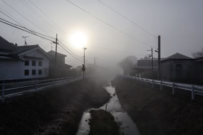 Houses along the river and the sun in the fog