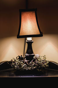 Close-up of illuminated lamp on table against wall at home