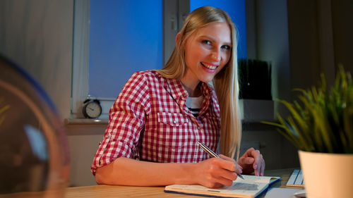 Portrait of smiling young woman writing in book