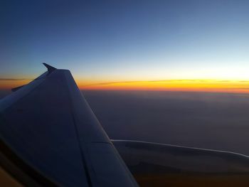Cropped image of airplane flying in sky at sunset