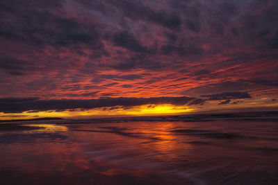 Scenic view of sea against dramatic sky during sunset