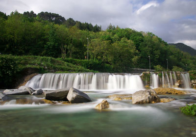 Scenic view of waterfall against sky