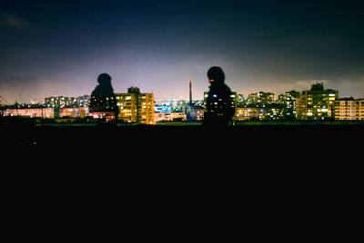 Silhouette buildings against sky in city at night