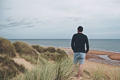 Rear view of man standing on standing on shore at beach