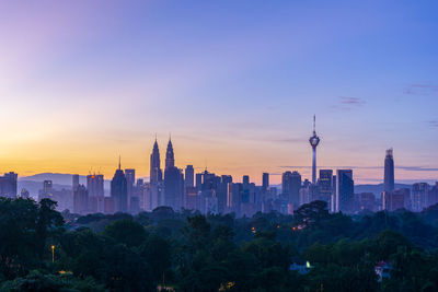 Modern buildings in city against sky during sunset