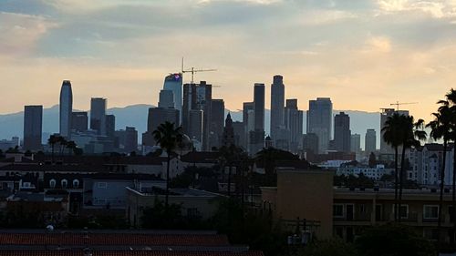 Buildings in city against sky during sunset