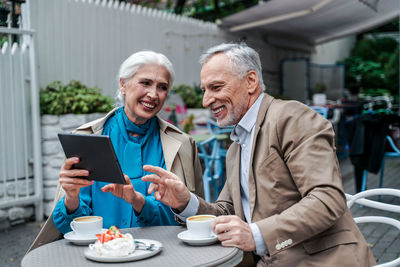 Man holding coffee while using smart phone at laptop