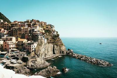 Scenic view of sea by buildings against clear sky