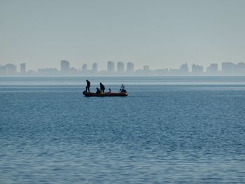 Rear view of man kayaking on sea against clear sky