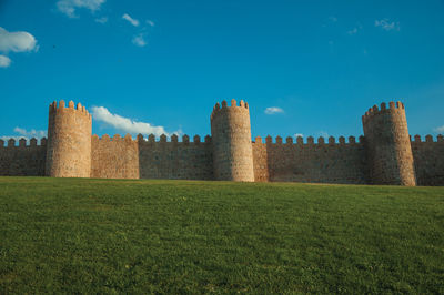 Castle on field against blue sky