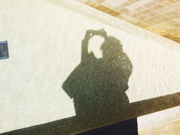 Shadow of human hand on tiled floor