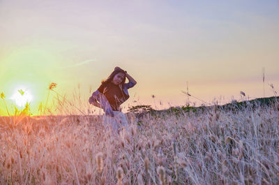 Portrait of young woman standing amidst plants against sky